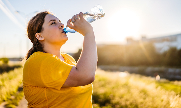 A woman drinking from a water bottle after exercising